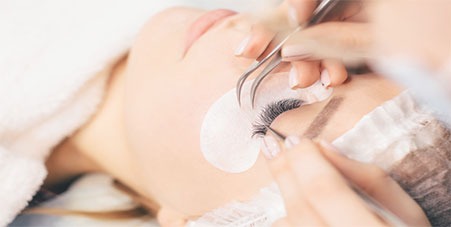Woman having eyelash extensions applied
